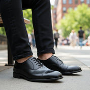 model-sitting-bench - Men's Black Leather Cap-Toe Derby Shoes